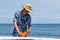 Surfer putting an orange fin into a surfboard in Japan, he is wearing a Hawaiian shirt and straw hat.