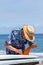 Surfer putting an orange fin into a surfboard in Japan, he is wearing a Hawaiian shirt and straw hat.