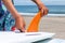 Surfer putting an orange fin into a surfboard in Japan, he is wearing a Hawaiian shirt and straw hat.
