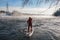 Surfer in a red wetsuit on a board with a paddle floats against the waves. Winter sup surfing on the Vuoksa river. Losev