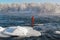 Surfer in a red wetsuit on a board with a paddle floats against the waves. Winter sup surfing on the Vuoksa river. Losev rapids