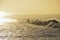 Surfer rides the golden ocean waves in the sunrise light.