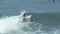 A surfer rides a wave in the surf at the ocean blue in the surf spot.