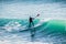 Surfer riding on stand up paddle board on big wave. Winter surfing in ocean