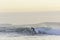 Surfer riding the wave in rough sea during sunset