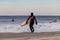 Surfer running into the ocean in a wetsuit. Cold weather surfing. Long Beach NY