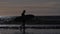 Surfer silhouette with his surfboard on the beach