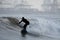 Surfer silhouette surfing the waves near commercial dock