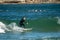 Surfer standing on the shortboard and catching waves, scattering water around