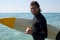 Surfer with surfboard standing at beach coast