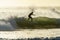 A surfer surfing at Betty`s Bay beach at sunset in the Western Cape, South Africa