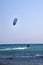 Surfer on a Wakeboard Flying a Traction Kite. Rider in Wetsuit Standing and Balancing on a Surfboard. Blue water and