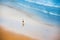 Surfer walking along a sandy beach carrying a surfboard