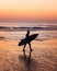 Surfer walking on a portuguese beach during sunset hours