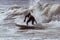 Surfer in a wetsuit carving through ocean waves. Winter cold weather surfing  - Long Beach, NY