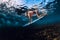 Surfer woman dive underwater with surfboard, under wave