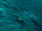 Surfer woman with surfboard in blue ocean. Aerial view with surface of sea