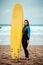 Surfer woman wearing wetsuit standing on the beach with a surfboard