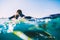 Surfer woman in wetsuit on the surfboard. Woman with surfboard in ocean during surfing
