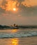 Surfers against ocean sunset background