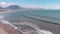 Surfers on boards surfing and waiting for waves. Group of young people sitting on boards in sea at windy day. Sea waves crashing o