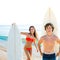 Surfers boy and teen girl with surfboard in beach