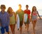 Surfers boys and girls group walking on beach