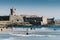 Surfers at Carcavelos beach, Lisbon Region, Portugal with historic fort in the