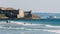 Surfers at Carcavelos beach, Lisbon Region, Portugal with historic fort in th