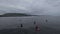 Surfers from a drone. Footage. Surfer greets and waves. Group of surfers. Grey view, sad weather. Drone aerial view.