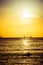 Surfers and sail boats in the ocean during sunset