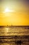 Surfers and sail boats in the ocean during sunset