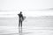 Surfers standing by the water`s edge at Llangennith Beach on the Gower Peninsula