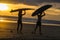 Surfers with surfboard on the beach at sunset