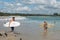 Surfers walk in the beach of Byron Bay.