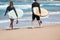 Surfers walking along the beach with surfboards