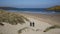 Surfers walking away from camera Crantock bay and beach North Cornwall England UK