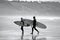 Surfers walking bavk from the water`s edge at Llangennith Beach on the Gower Peninsula