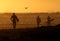 Surfers walking down the beach at sunset