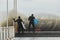surfers in wetsuits with surfboard on a city pier amid powerful waves in Australia. Concept: confrontation between the