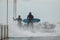 Surfers in wetsuits with surfboard on a city pier amid powerful waves in Australia. Concept: confrontation between the
