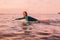 Surfgirl with perfect body on a surfboard floating in ocean