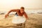 Surfing freelancing man muscle and press sport training on the beach at sunset.male fitness model surfer with a big surf