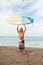 Surfing. Handsome Surfer Holding White Surfboard Above Head. Smiling Man Standing On Sandy Beach Portrait.