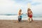 Surfing. Handsome Surfers Standing On Sunny Beach. Cheerful Men Giving Fist Bump Near Surfboards In Sand.