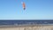Surfing at the sea with a red parachute at strong wind and waves. kitesurfing.