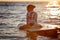 Surfing and vacation. Holiday on the beach. Relaxed little girl sitting on the water with surfboard enjoying the sunset