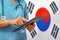 Surgeon or doctor using a digital tablet on the background of the South Korea flag