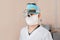 Surgeon man in a mask in special medical clothes wearing glasses with a binocular magnifying loupes is standing