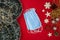 Surgical mask in Christmas composition. Decorated Christmas background with christmassy ornaments and decorations. Top view with